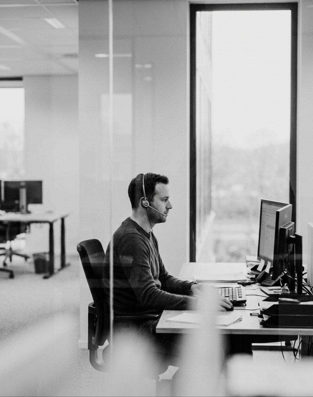 Medewerker klantcontact met headset aan een bureau bij het raam