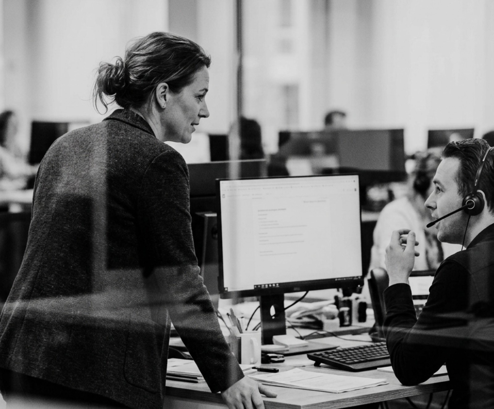 Een teamleider klantcontact kijkt mee bij een collega met headset
